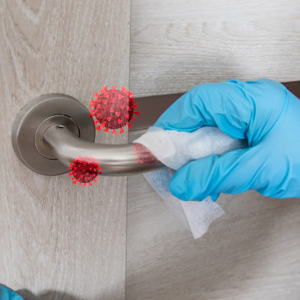 A person with blue gloves disinfecting a door handle