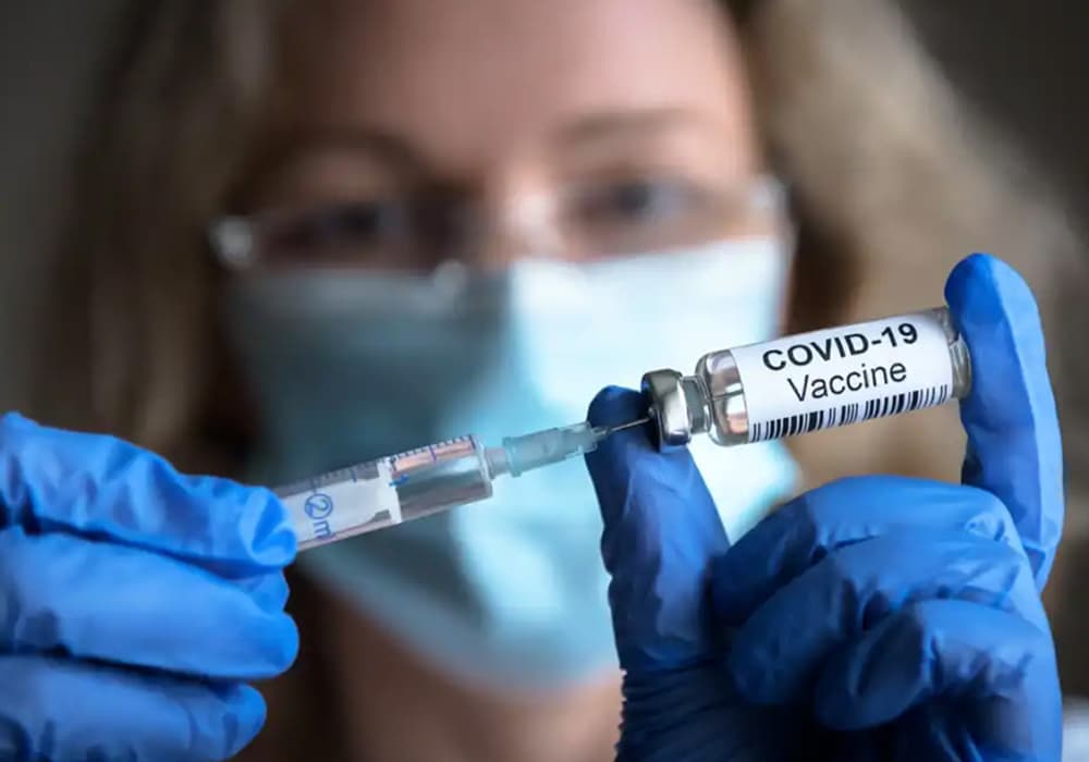 A woman wearing clue gloves preparing a covid-19 vaccine