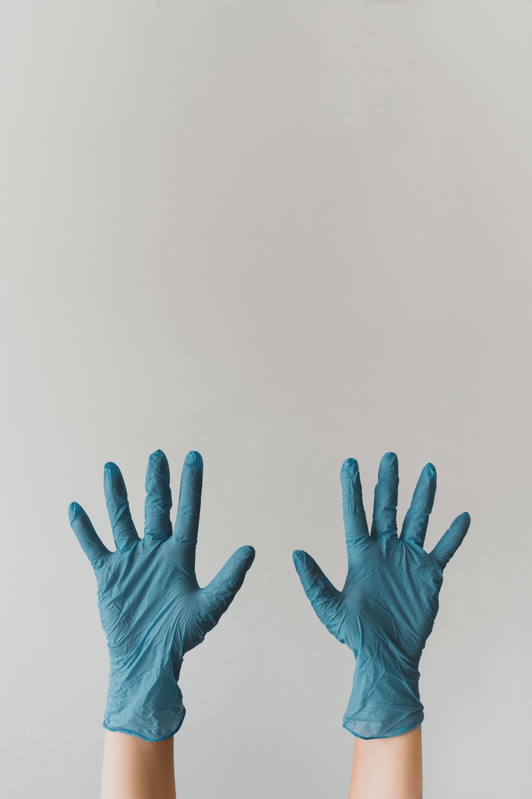A person wearing blue gloves holding up their hands