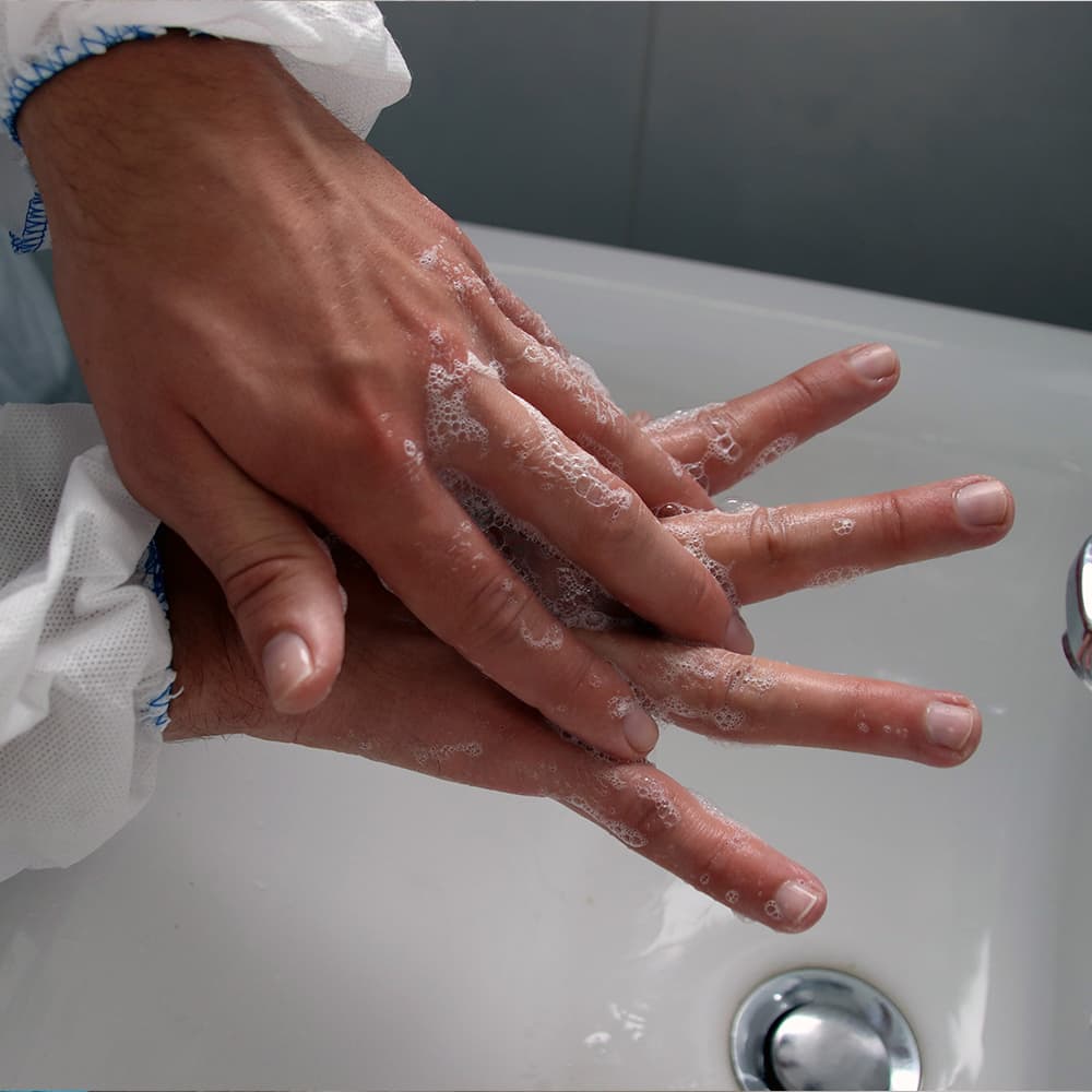 A person lathering and washing their hands over a sink