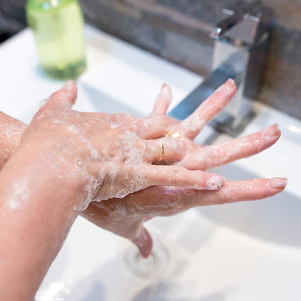 A White woman washing her hands with soap