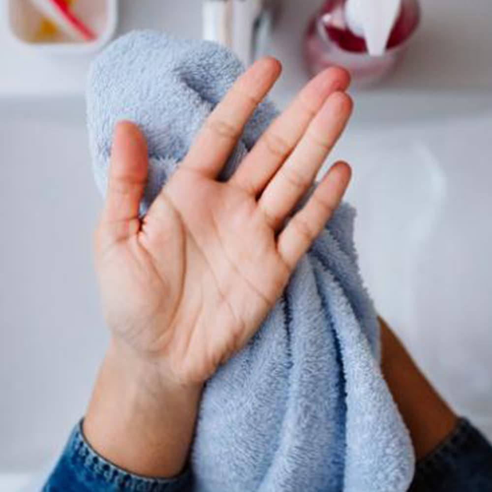 Drying hands with a blue towel after washing them
